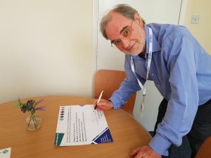 David N Jones, Chair of Healthwatch Northamptonshire, signing the wellbeing pledge